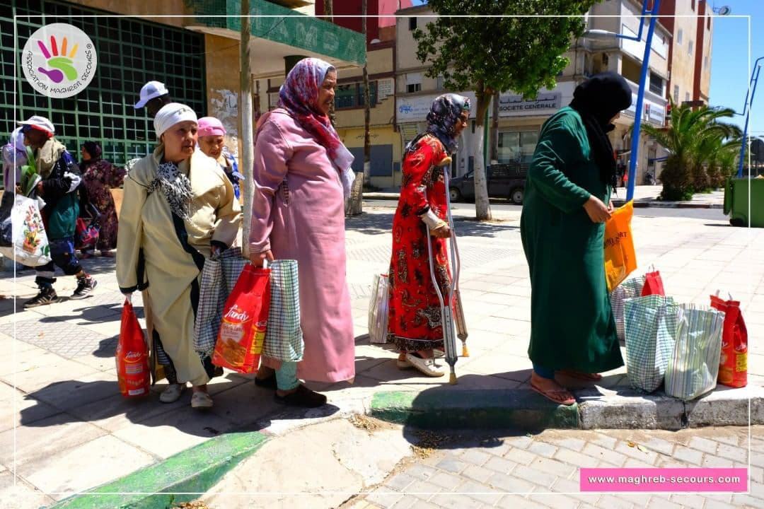 Femmes recevant des sacs de denrées alimentaires lors d'une distribution urbaine de Maghreb Secours